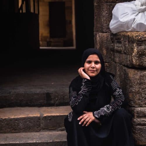 portrait shot of woman in Old Black with a headscarf posing for me with a serious face in Old Cairo.