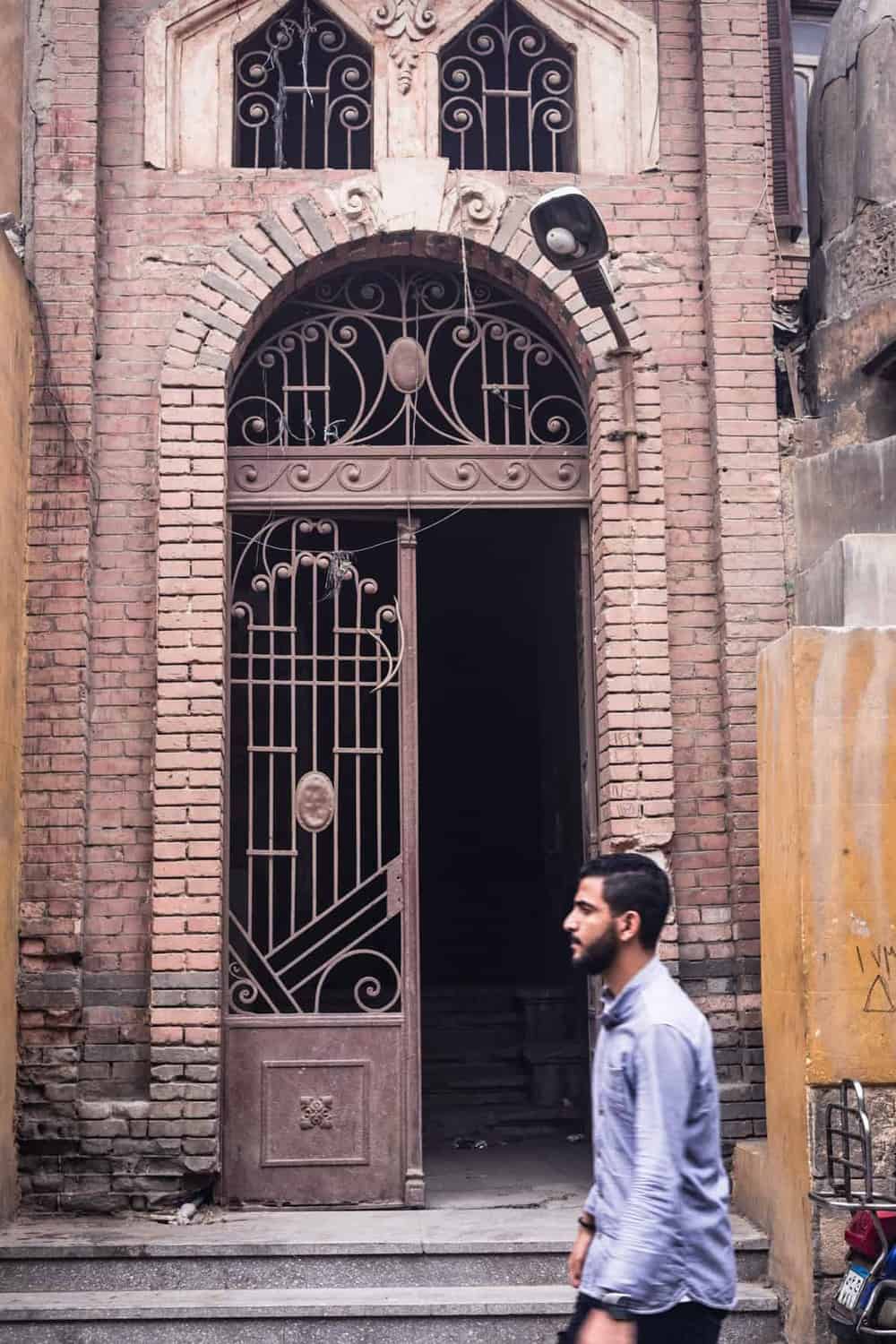 Man passing a gorgeous old gate in Old Cairo.