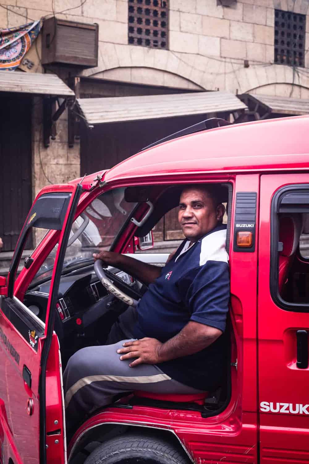 portrait shot of a man sitting in a red trunk, posing for my camera in Old Cairo.
