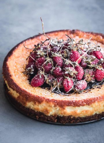 Mascarpone Cheesecake with balsamic roasted long stemmed strawberries, out of the spring form pan, 45 degree angle shot.