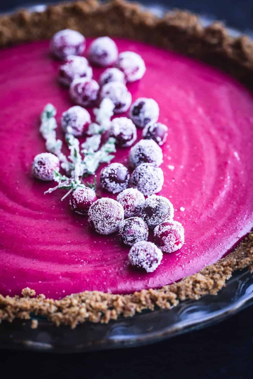 Cranberry Gingersnap Pie. Topped with sugared cranberries and sugared thyme. Side Ange shot. Up close. On a black background.