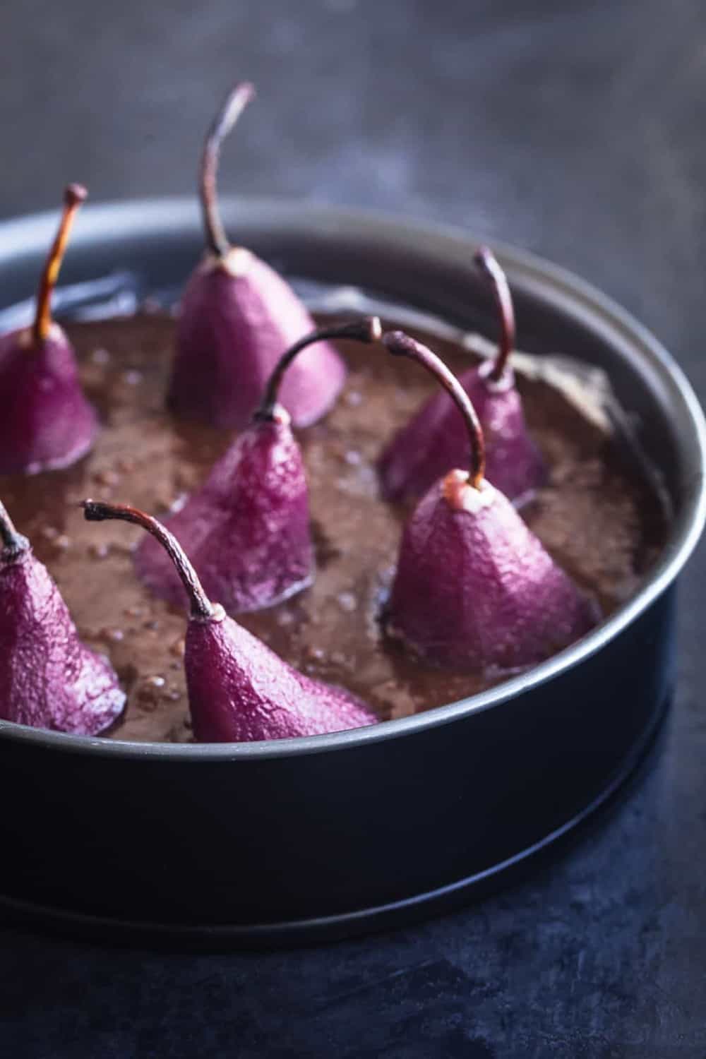 Spiced red wine poached pears in chocolate cake batter, in cake pan, pre oven.