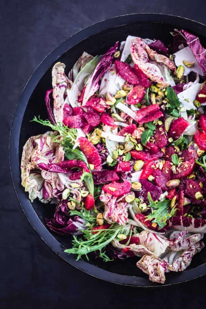 Blood Orange & Fennel Salad with chicories, ricotta salata, pistachios and mint in a large dark bowl.