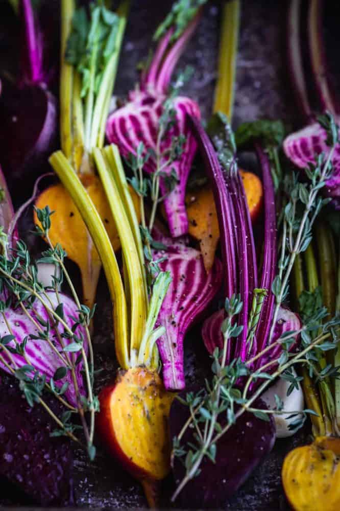 Up close shot of baby beets cut in half tossed with garlic and thyme.
