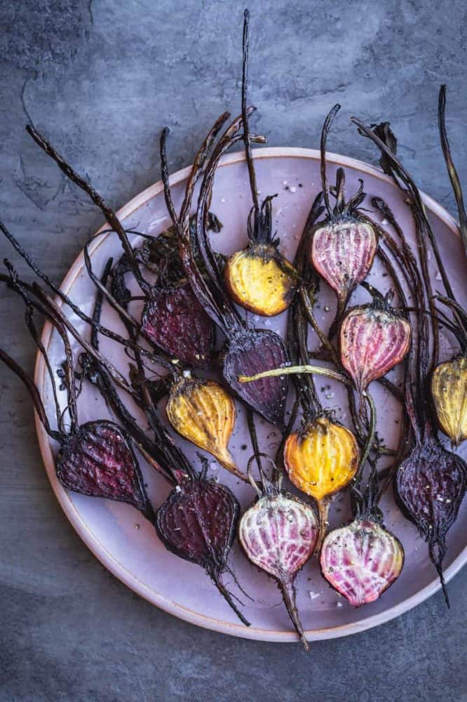 Baby beets after being roasted and arranged on a pink plate.