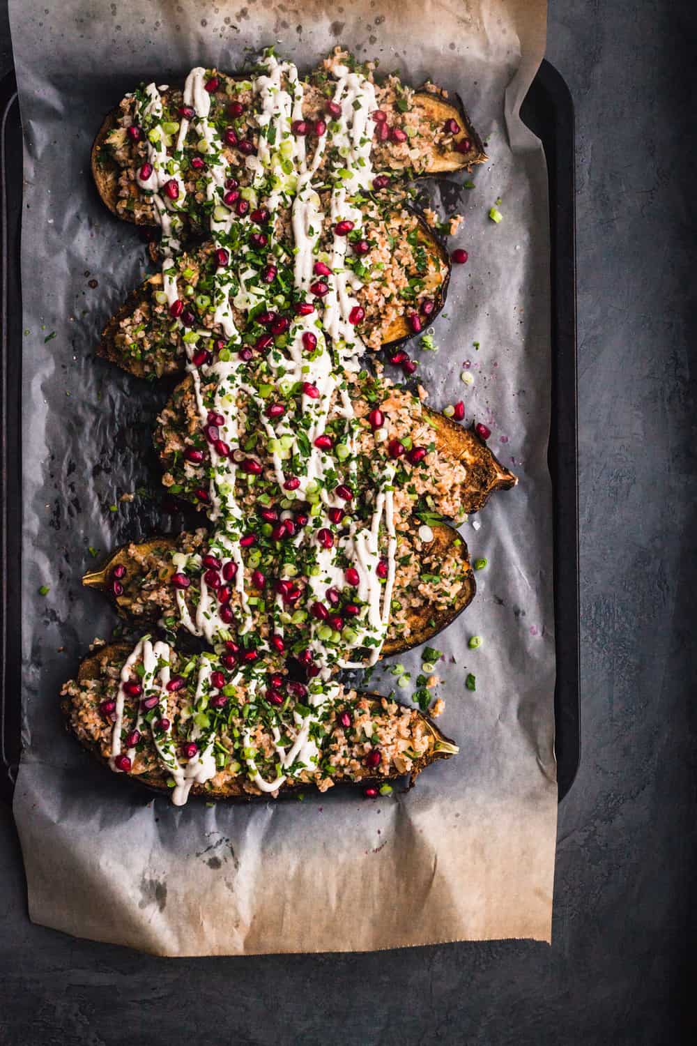 Bulgar Stuffed Eggplant with fresh herbs, tahini drizzle and pomegranate seeds all done and ready to be eaten.