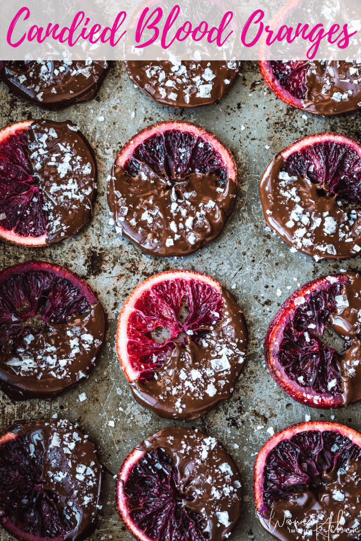 Candied Blood Oranges dipped in Chocolate with Flaky Sea Salt on a pan.