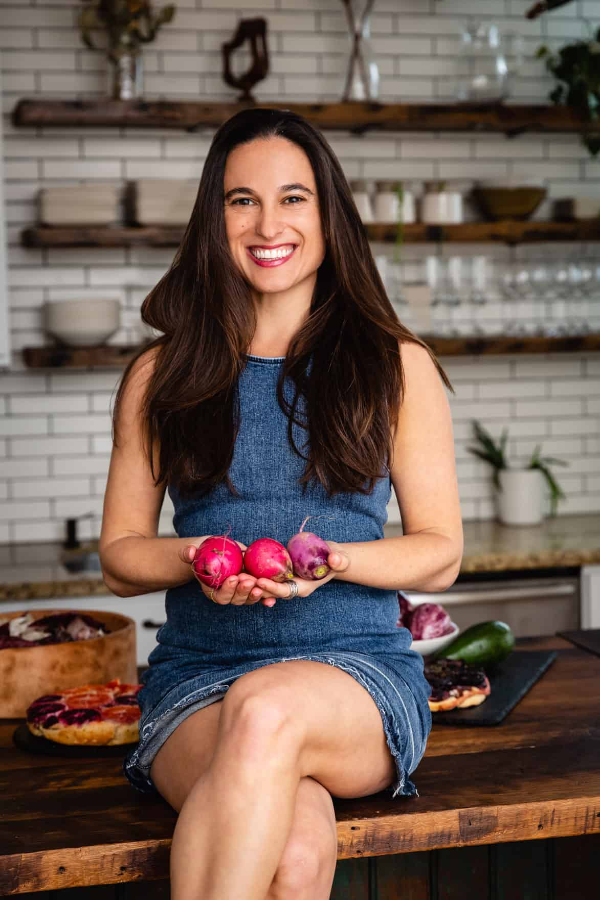 Chef Daniela Gerson in the kitchen holding root veggies.