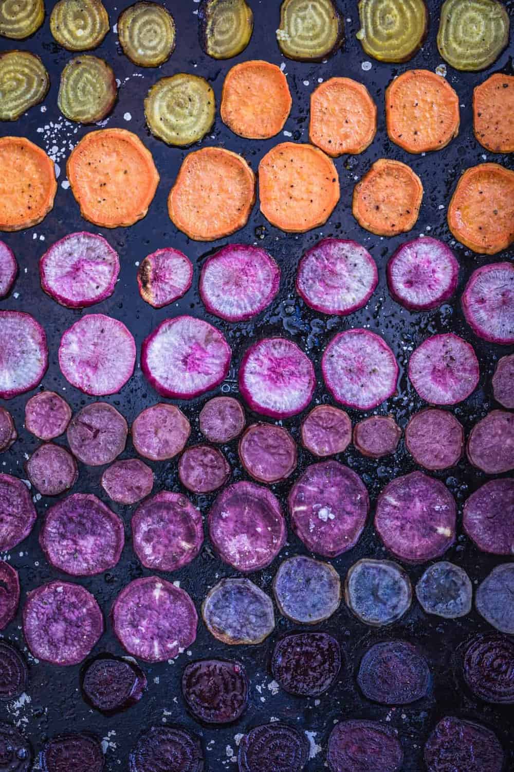 Rainbow Root Veggies in yellow, orange, pink, purple and deep red all sliced up and post oven shot.