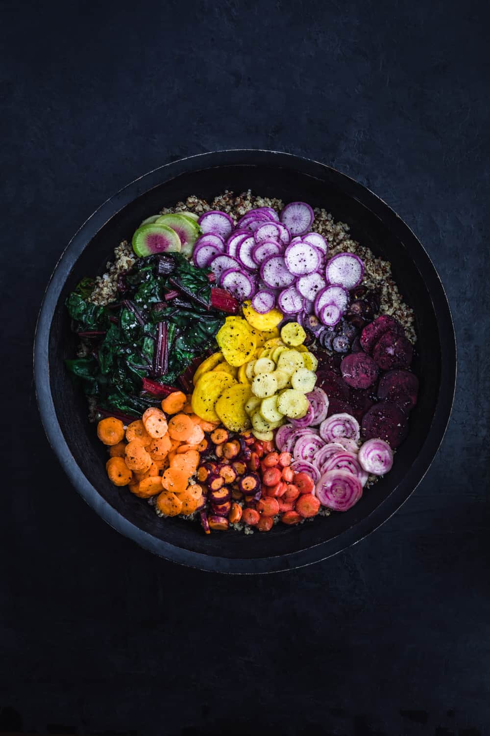 Veggie Rainbow Quinoa Bowl all arranged in a big dark bowl, without any drizzle yet.