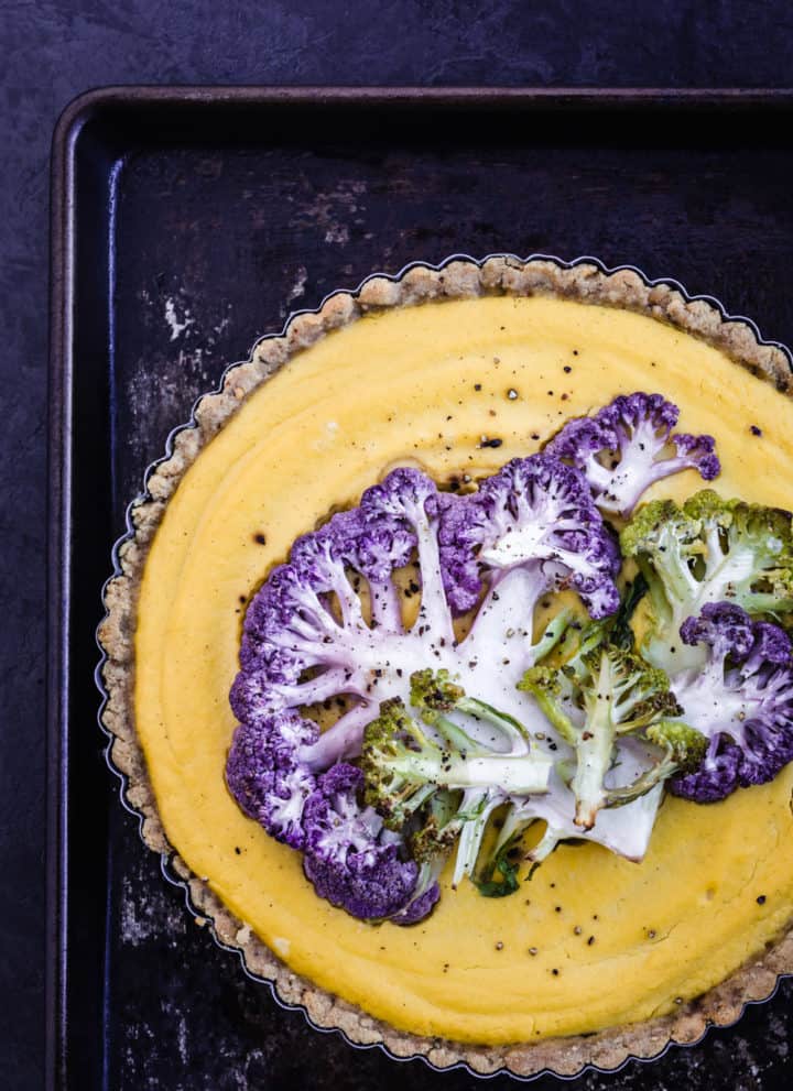 Yellow cauliflower tart, topped with purple and green thinly sliced cauliflower, post-oven.