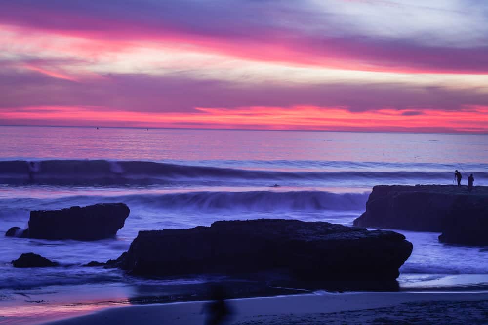 A pink and purple sunset in Santa Cruz over the ocean with waves coming in