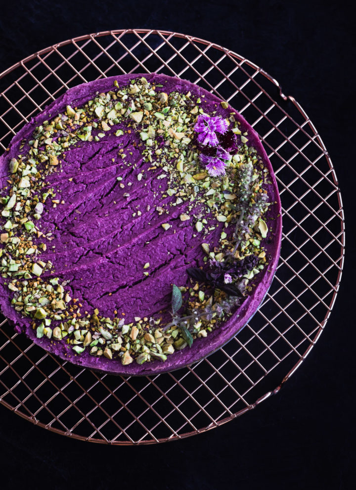 Purple sweet potato cheesecake topped with pistachios and edible flowers.