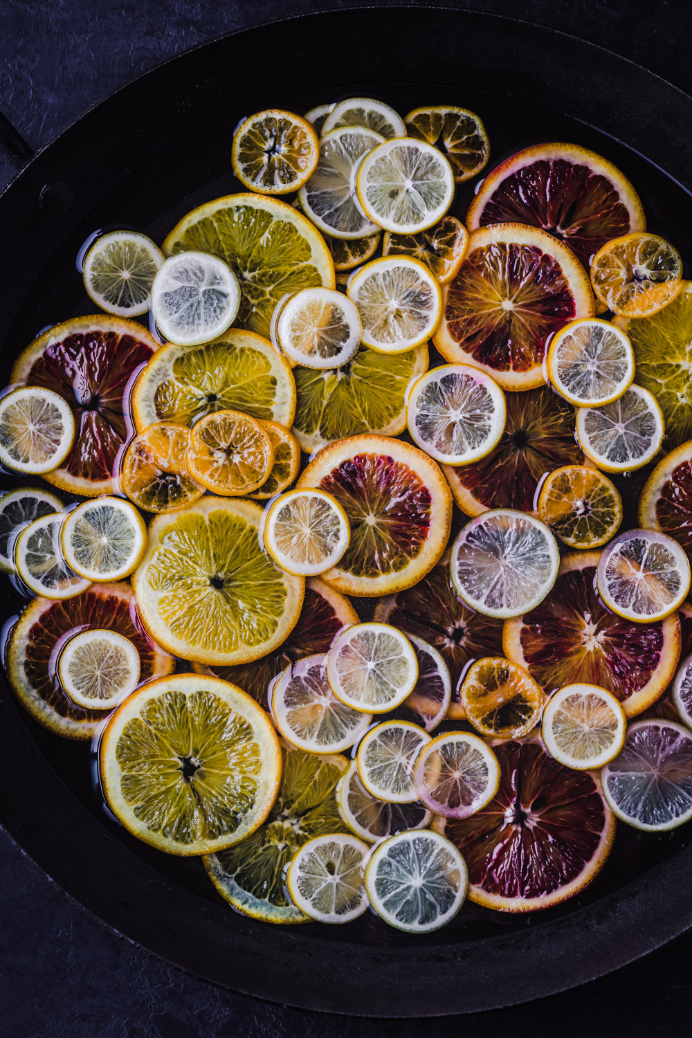An assortment of citrus simmering in simple syrup. In process shot of citrus being candied!