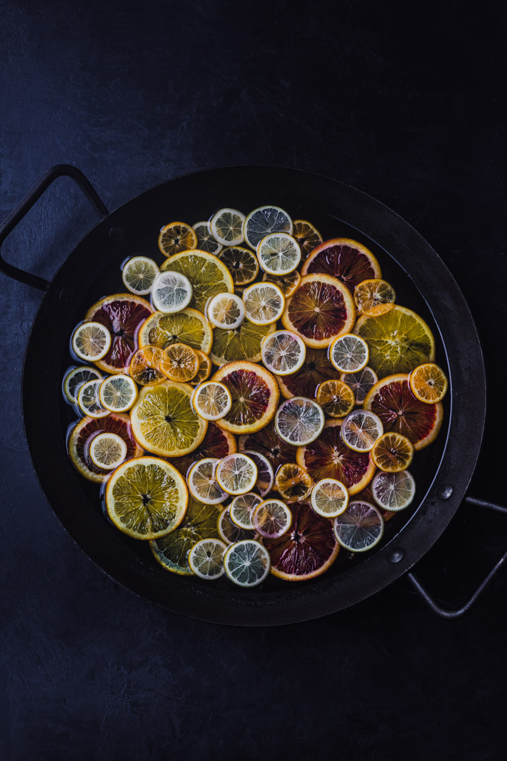 In process shot of an assortment of very colorful citrus simmering in simple syrup.