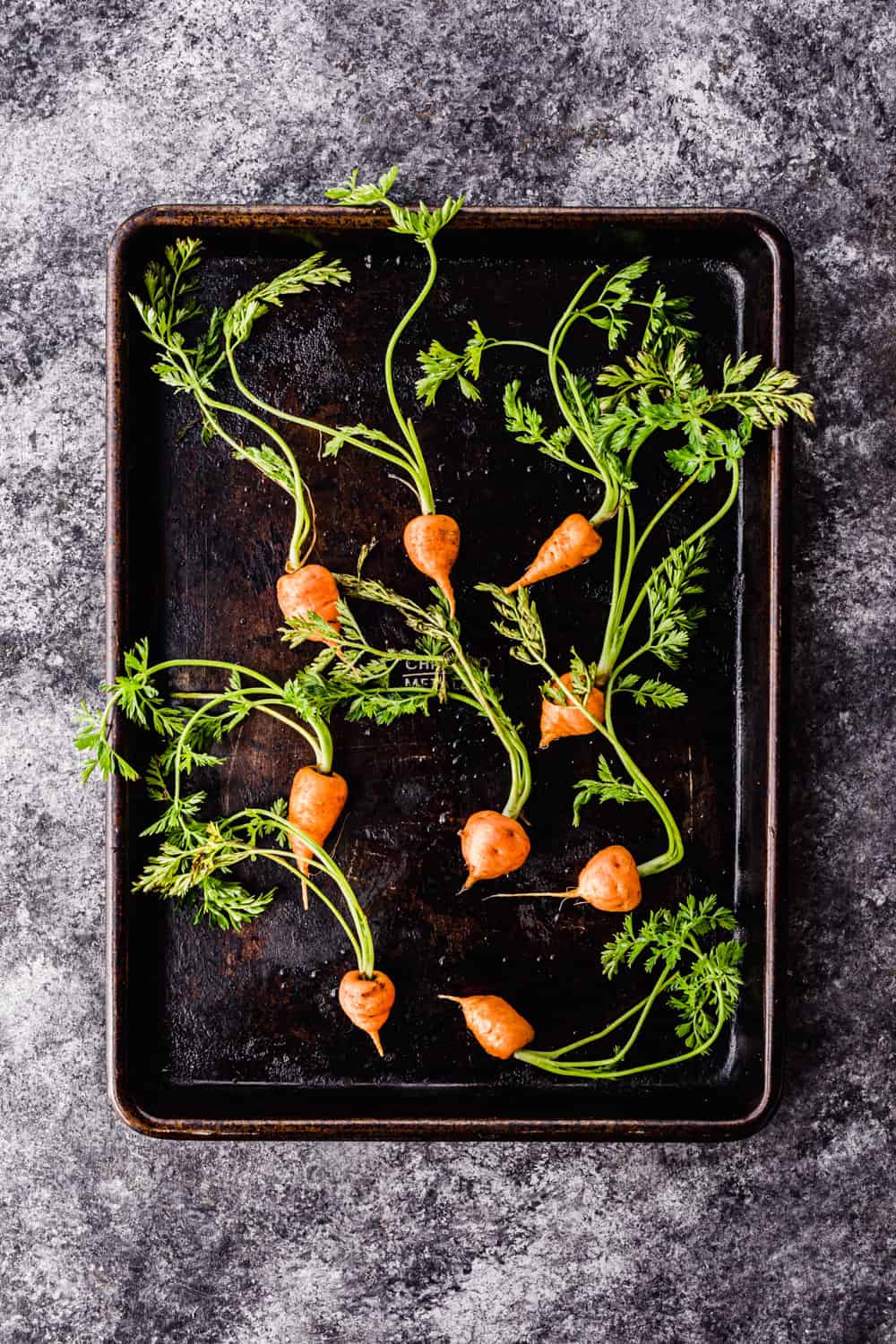 raw baby carrots on a baking sheet to be used in the farmers market salad