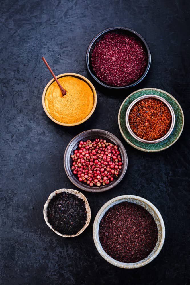ingredient shot of 6 spices in little bowls on a black background