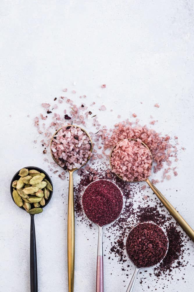 ingredient shot of 2 salts and 3 spices in spoons on a white background