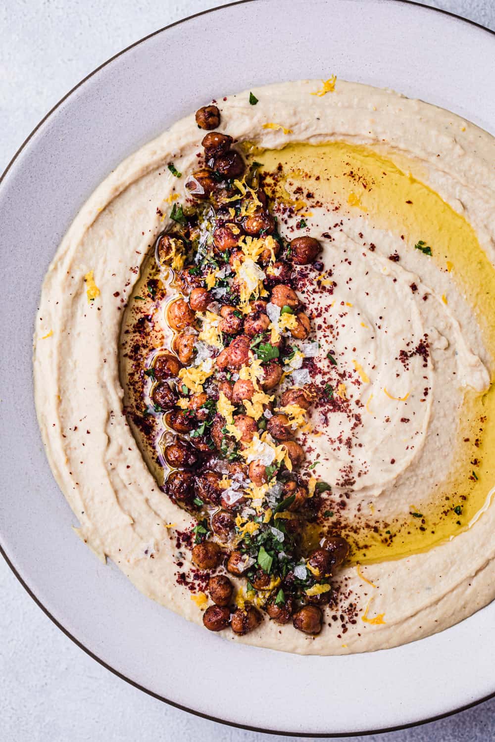 overhead shot of hummus with crispy chickpeas, lemon zest, spices and olive oil, close up and overhead shot