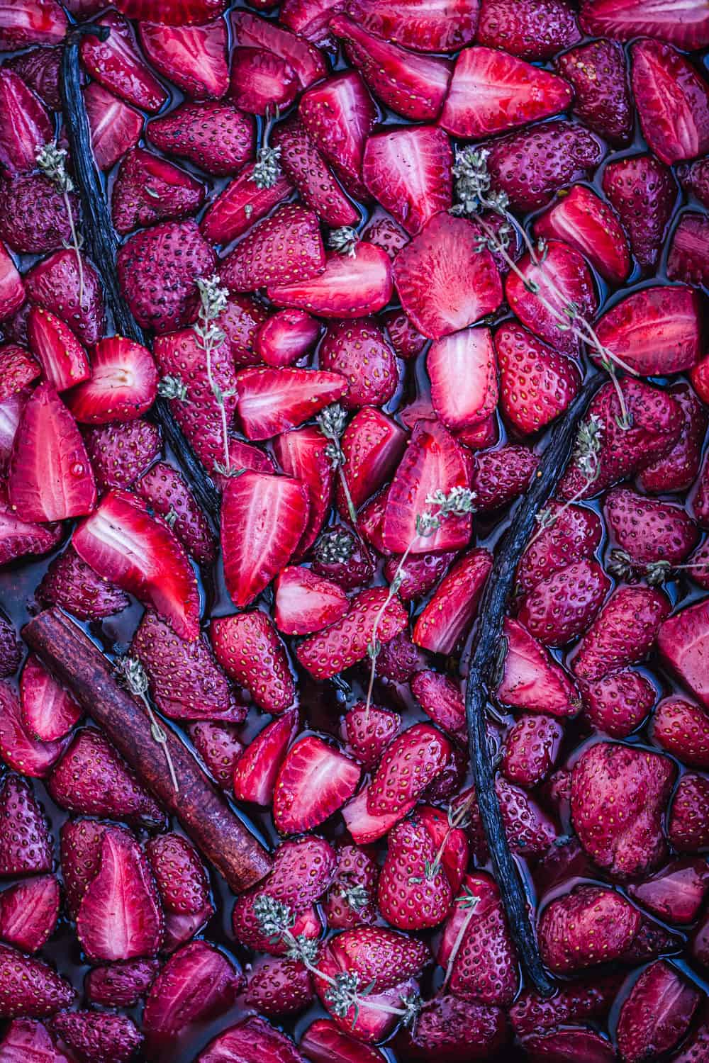 Cooked strawberries were roasted with thyme and vanilla just out of the oven, overhead shot.
