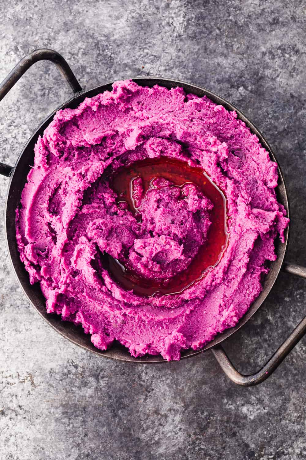 Purple sweet potato mash! Served in a little black cast iron dish with an olive oil swirl; overhead shot.