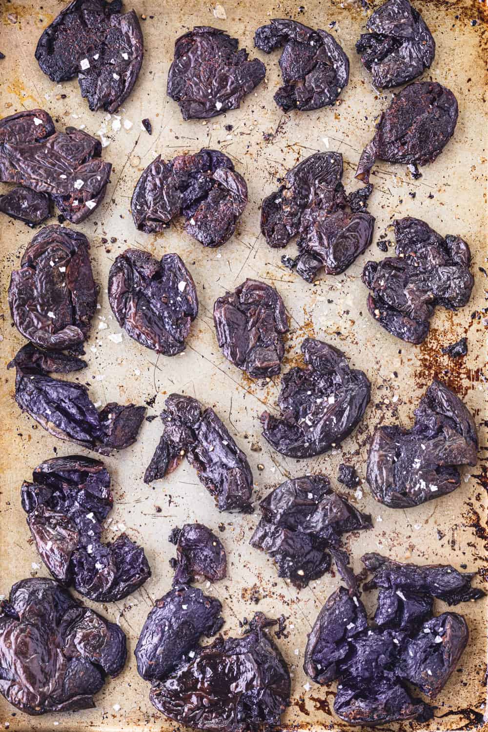 Purple smashed potatoes just out of the oven; on gold(ish) baking sheet and overhead shot.