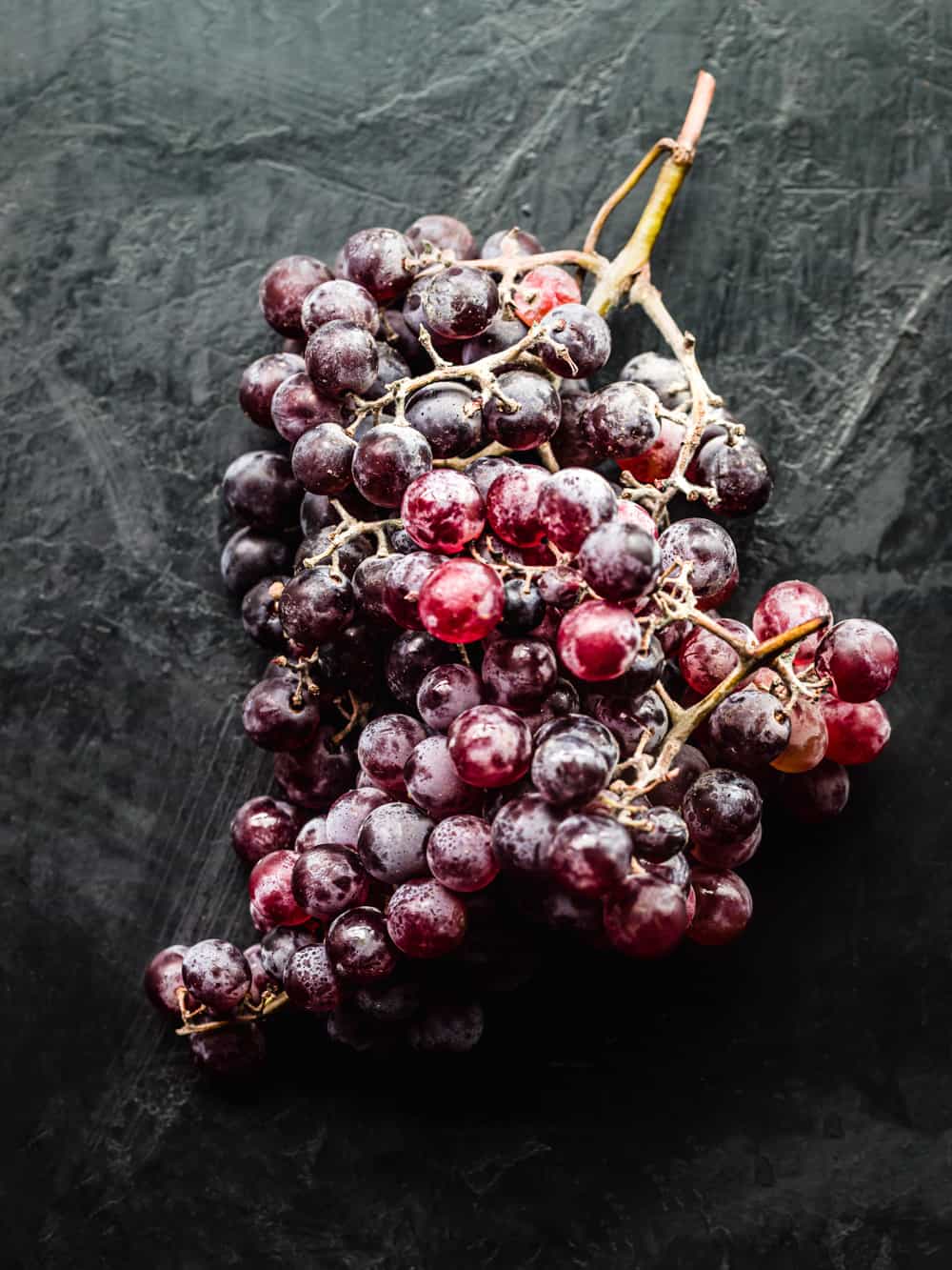 grapes on the vine on a black background; overhead shot.