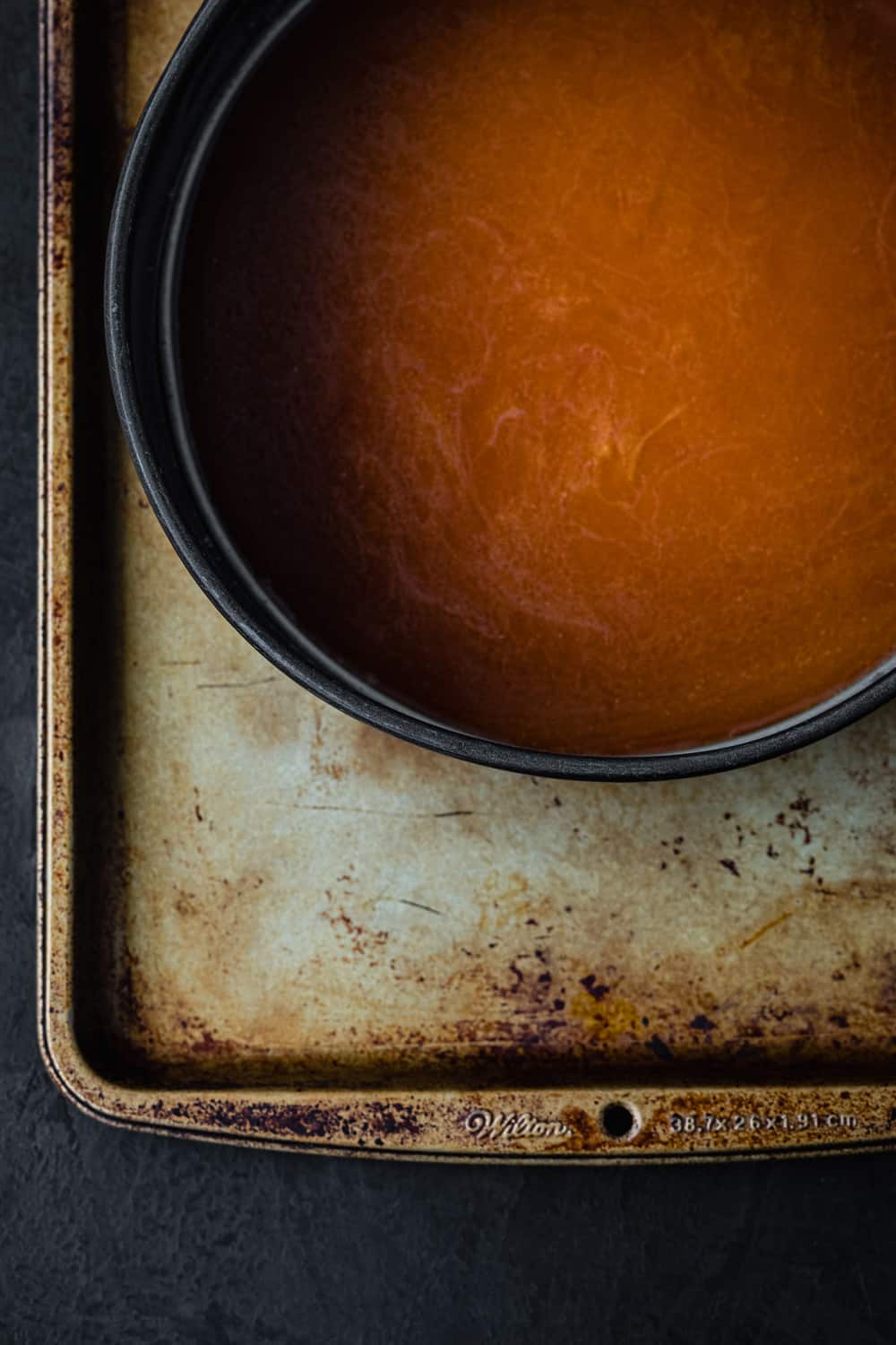Carmel poured into springform pan; on a gold sheet tray; overhead shot