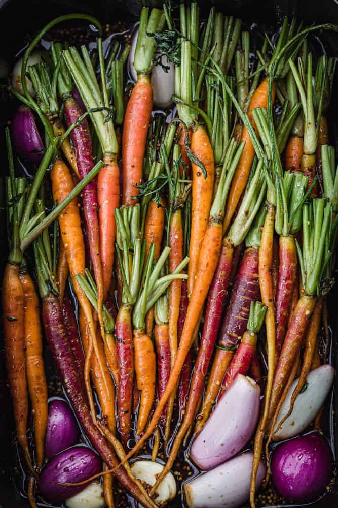 Rainbow roasted carrots with shallots in a baking dish; overhead shot