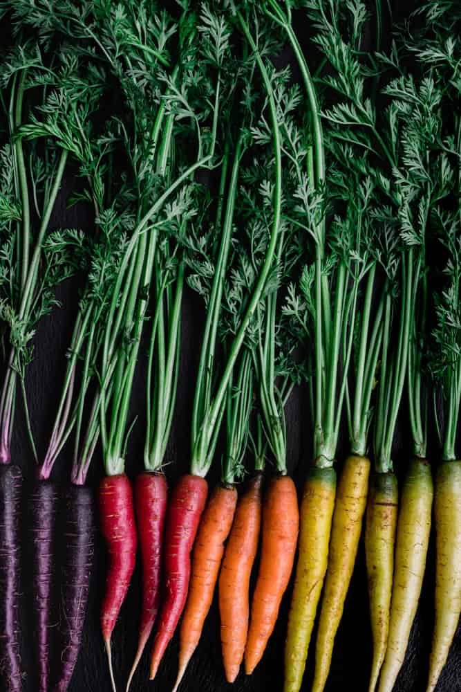 A carrot rainbow! Purple, pink, orange and yellow carrots lined up, side-by-side.