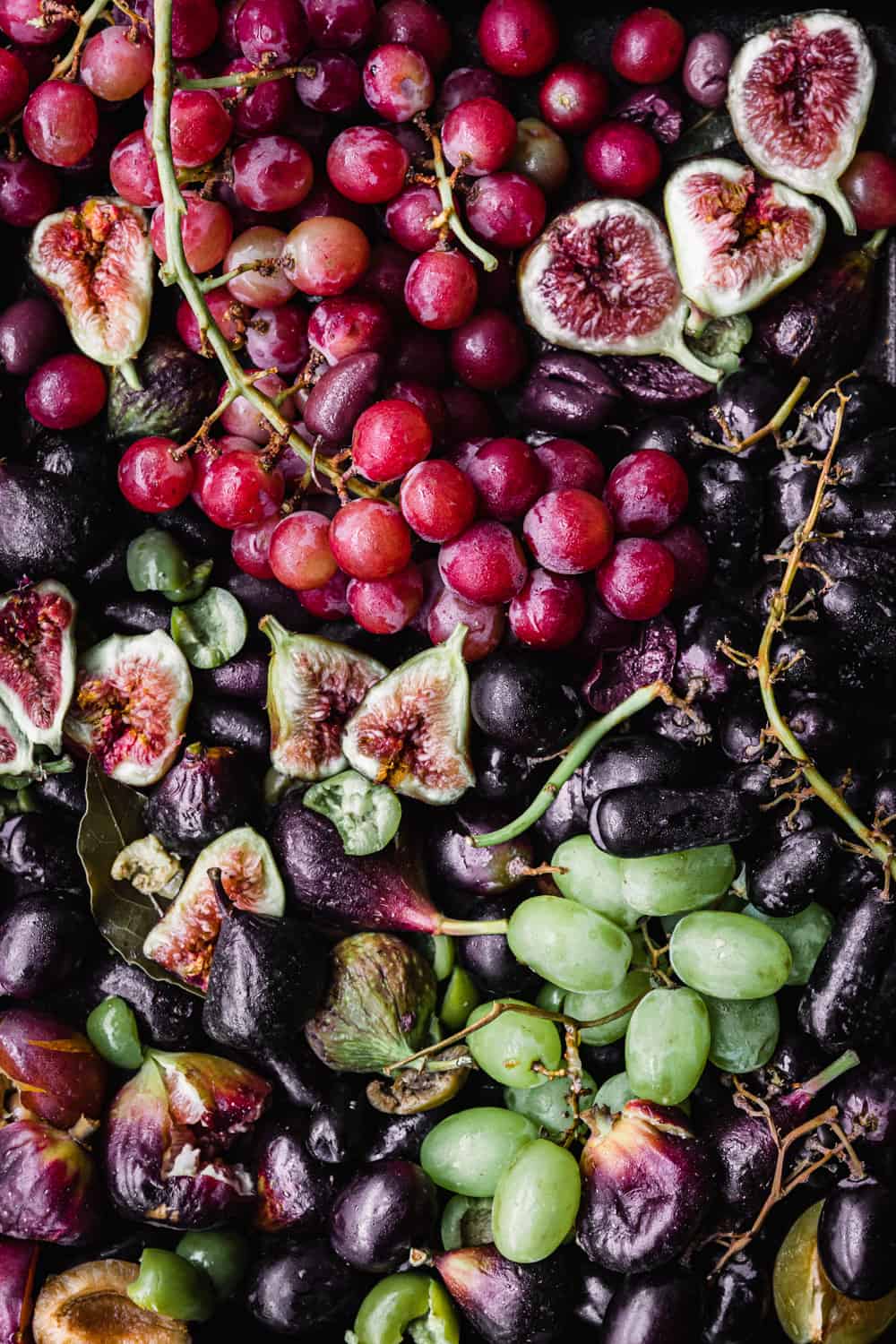 Colorful grapes and figs on a baking sheet; overhead shot