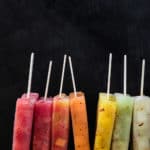 Colorful melon popsicles on top of red, orange, yellow and green melon ice.