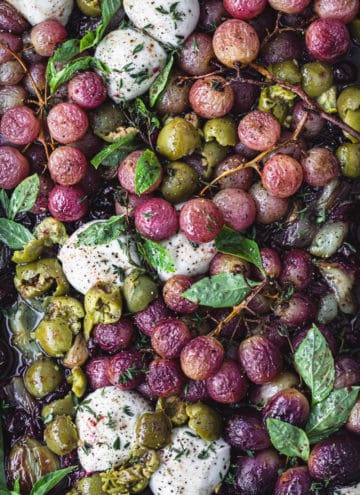 Roast Roasted grapes topped with burrata, olives and fresh herbs; overhead shot