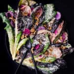 Tahini Caesar salad with walnut breadcrumbs and radishes on a black plate