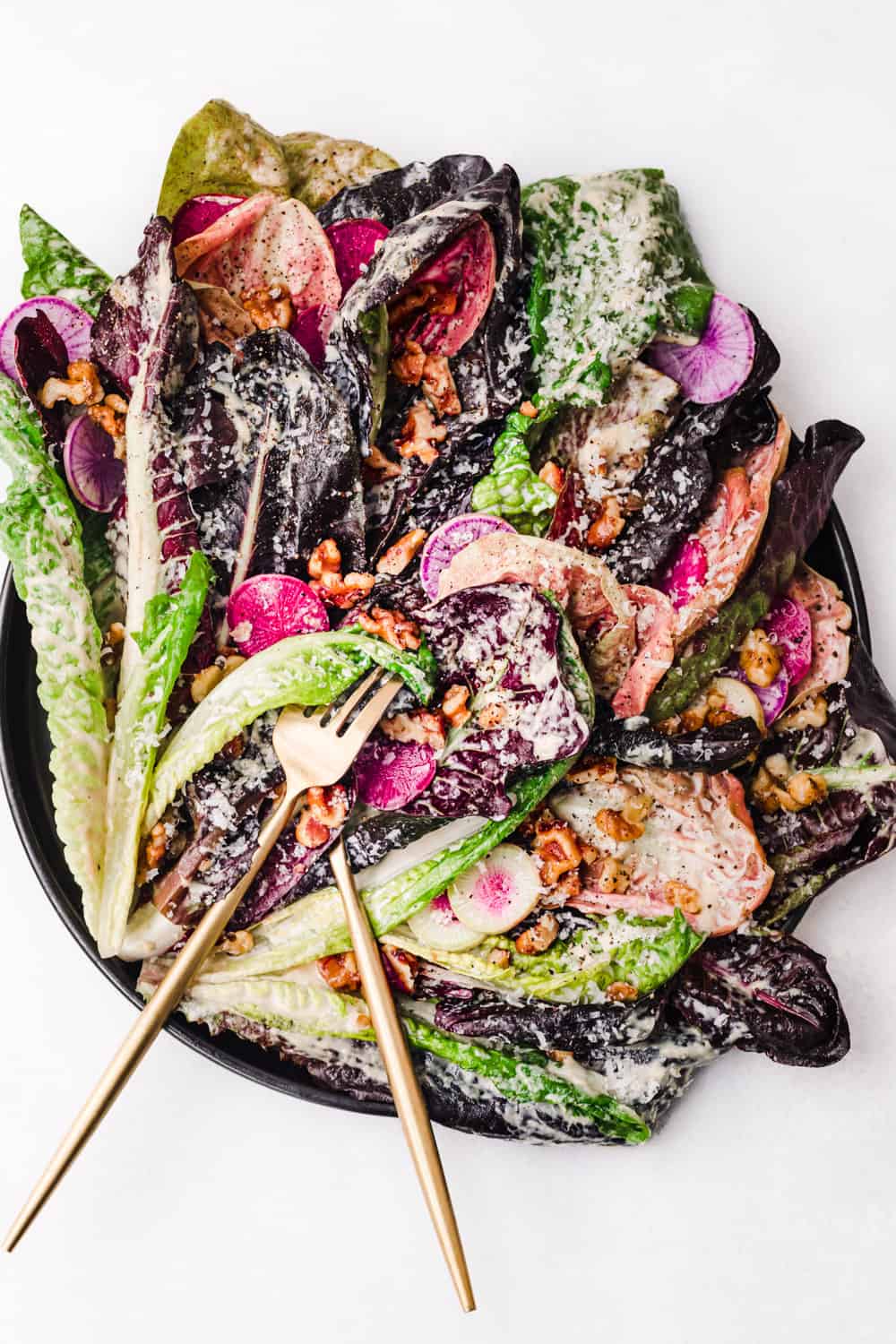 a vegan tahini Caesar salad with pink and purple radishes and breadcrumbs.