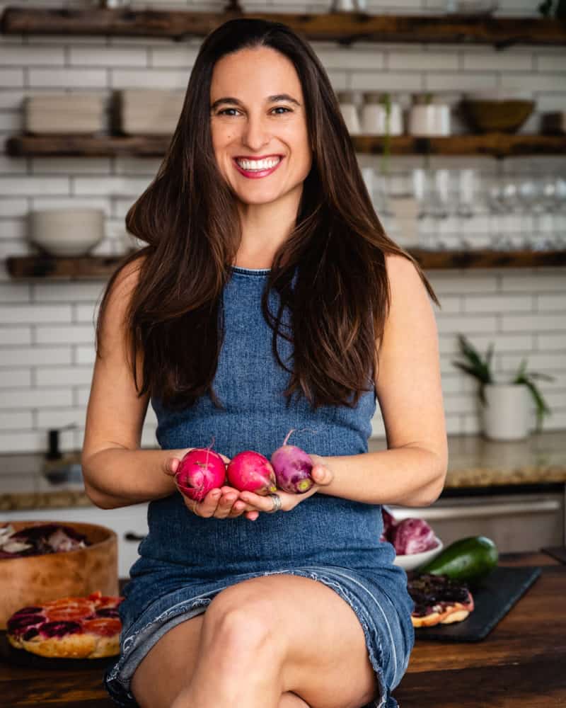Daniela Gerson in the kitchen holding root veggies.