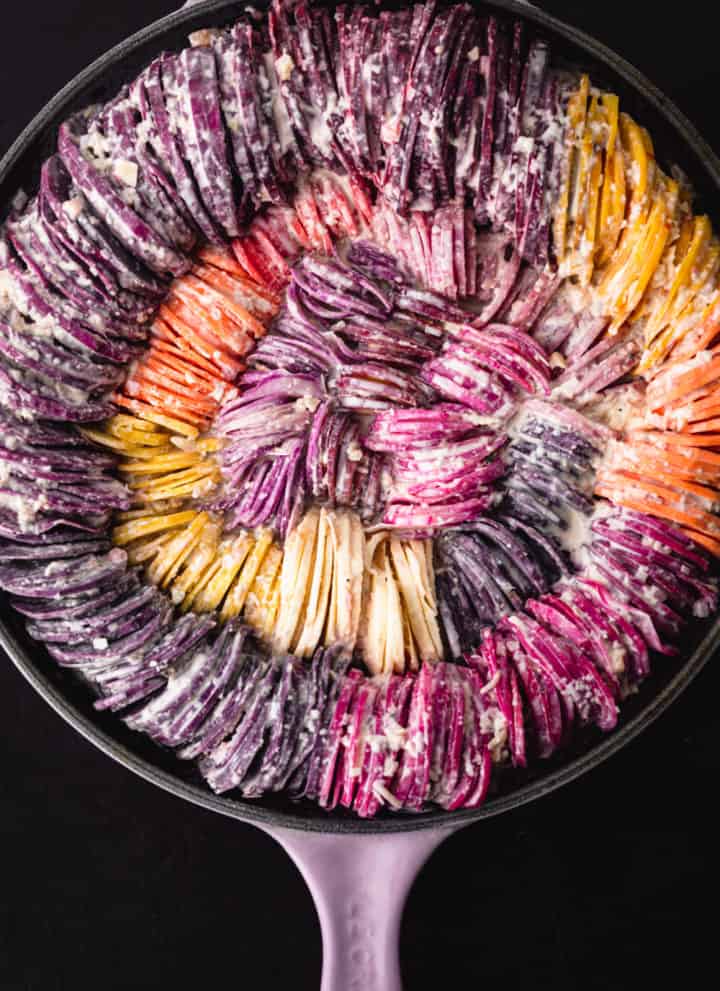 Rainbow root veggies including carrots, beets, potatoes, sweet potatoes, radishes and parsnips made into a very colorful hasselback gratin; proven shot.