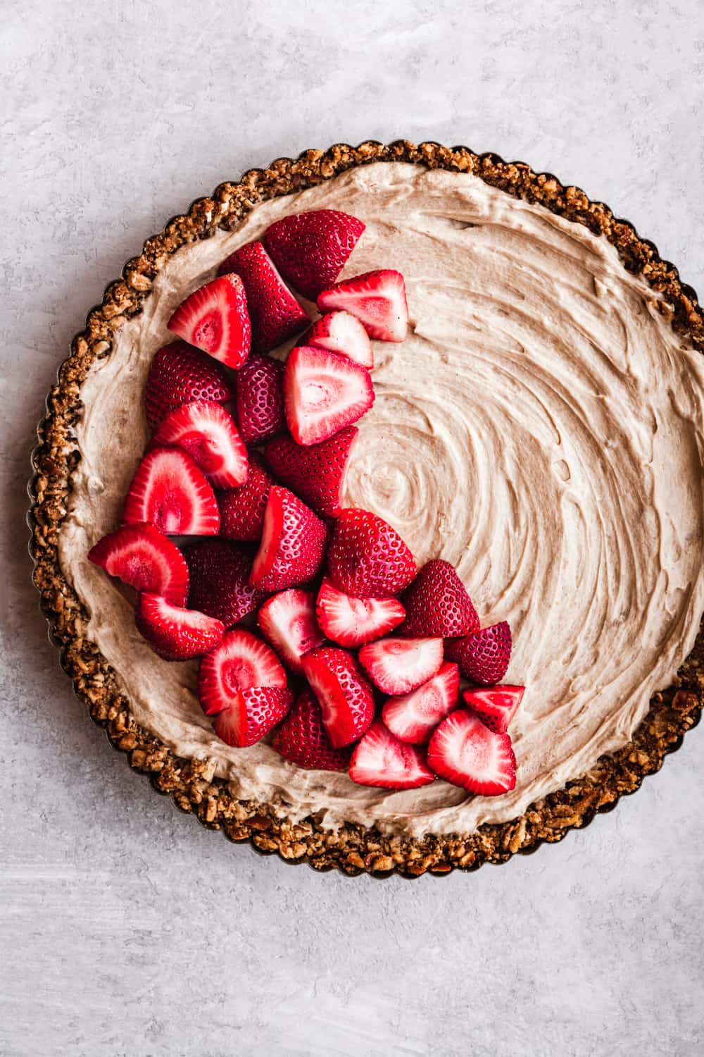 No-Bake Mascarpone Cheesecake with mascarpone, a pretzel crust, and topped with fresh strawberries. Overhead shot on a white background.