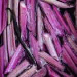 Vanilla poached rhubarb with a whole pod of vanilla in baking pan, directly off stove.