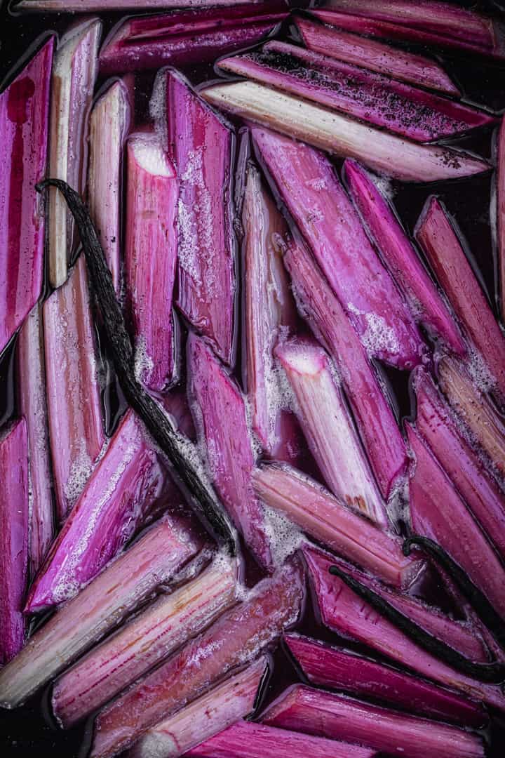 Vanilla poached rhubarb with a whole pod of vanilla in baking pan, directly off stove.