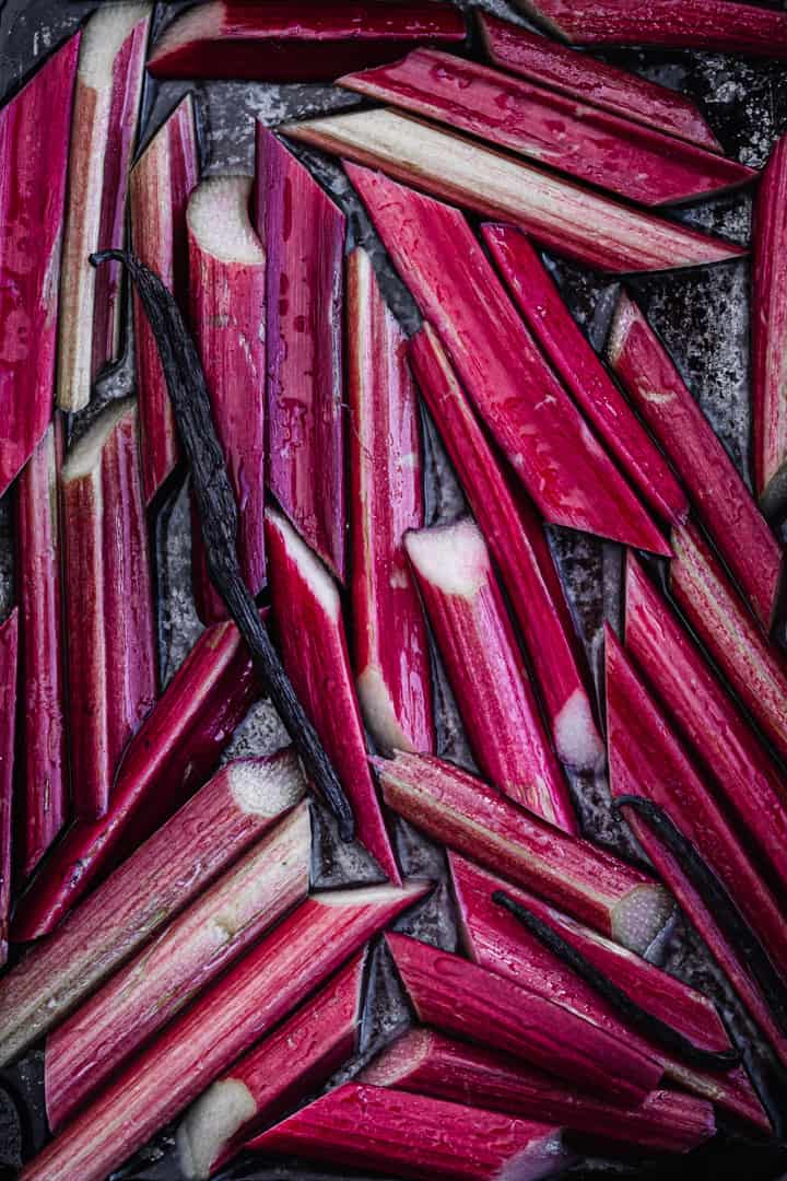 prepped and sliced hot pink stalks of rhubarb in baking pan with vanilla; up close and overhead shot