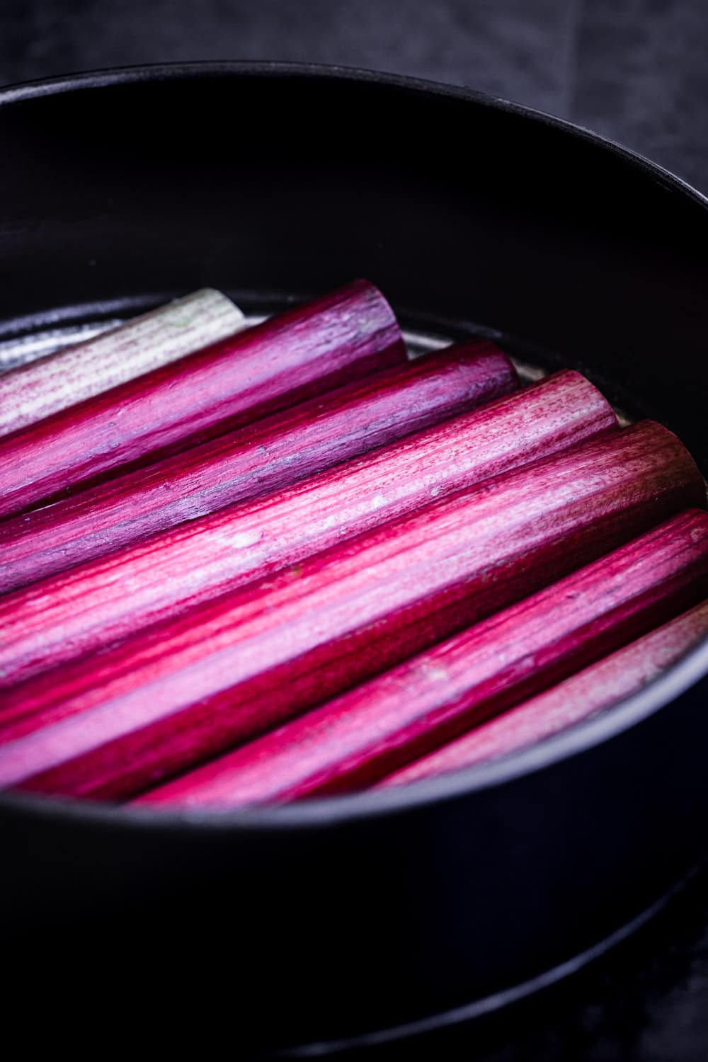 Rhubarb stalks aligned in the cake pan, side angle shot.
