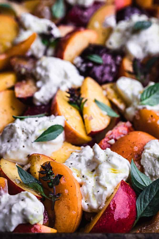 Side angle and up close shot of peaches and burrata salad with basil and vinaigrette.