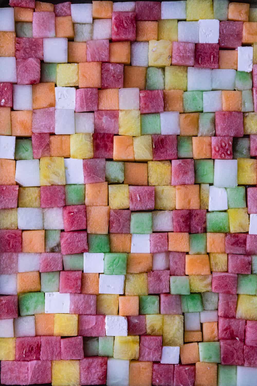 Watermelon feta salad with red, pink, orange, yellow, green and white melon and feta cut into cubes side by side.