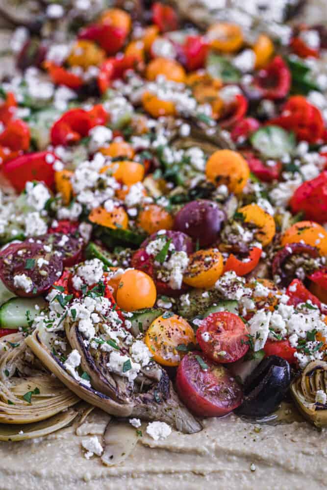 loaded hummus with very colorful toppings like cucumbers, feta, olives and more