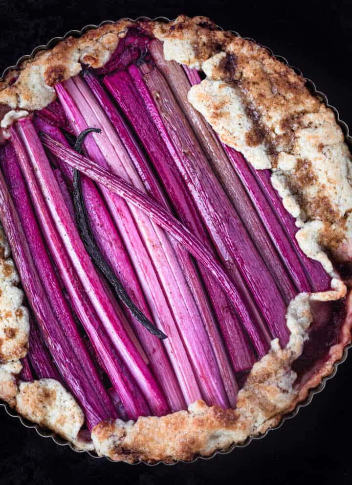 Rhubarb Galette with a whole vanilla bean straight out of the oven, in a tart pan and overhead shot.