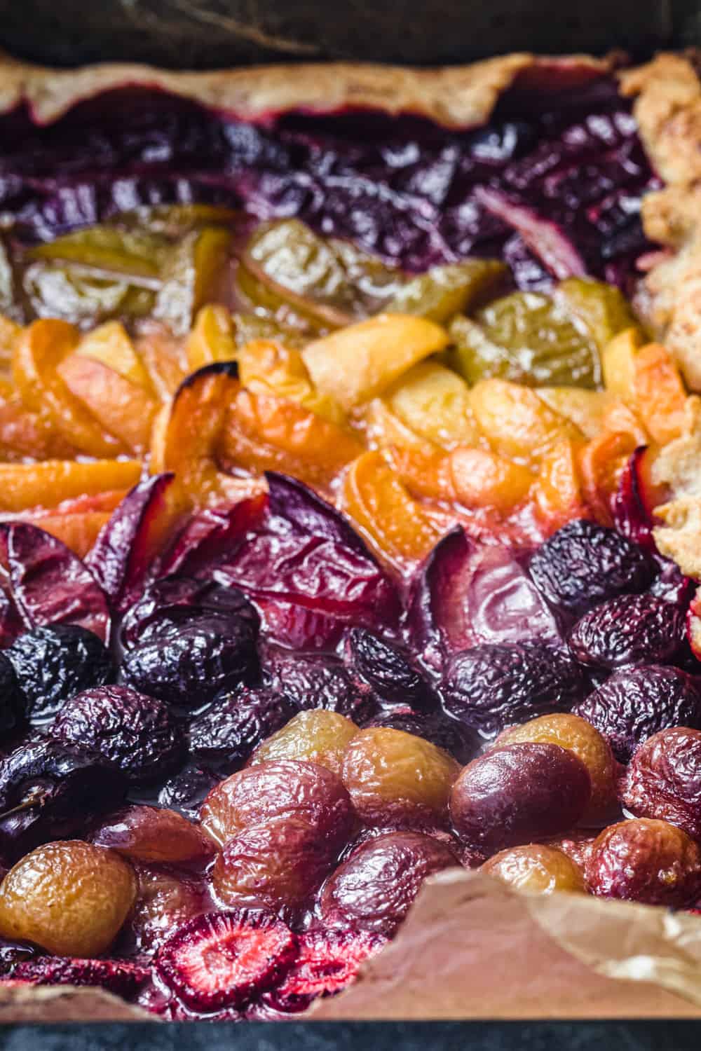 colorful stone galette just out of the oven with strawberries, cherries, apricots, plums and pluots; up close and side angle.