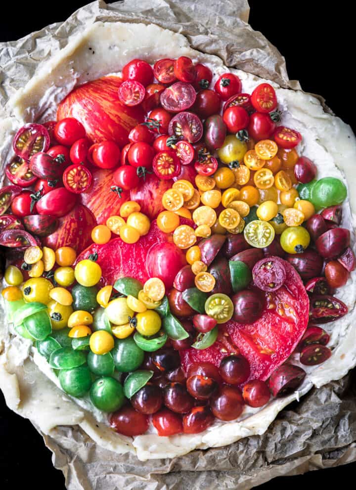 a raw and round tomato galette with red, orange, yellow and green tomatoes