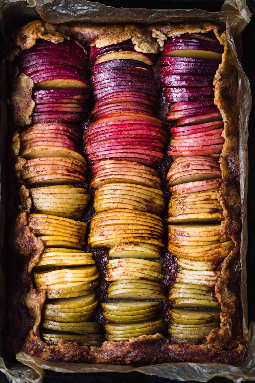 Spiced rainbow apple galette with purple, red, pink, orange and green apple slices.