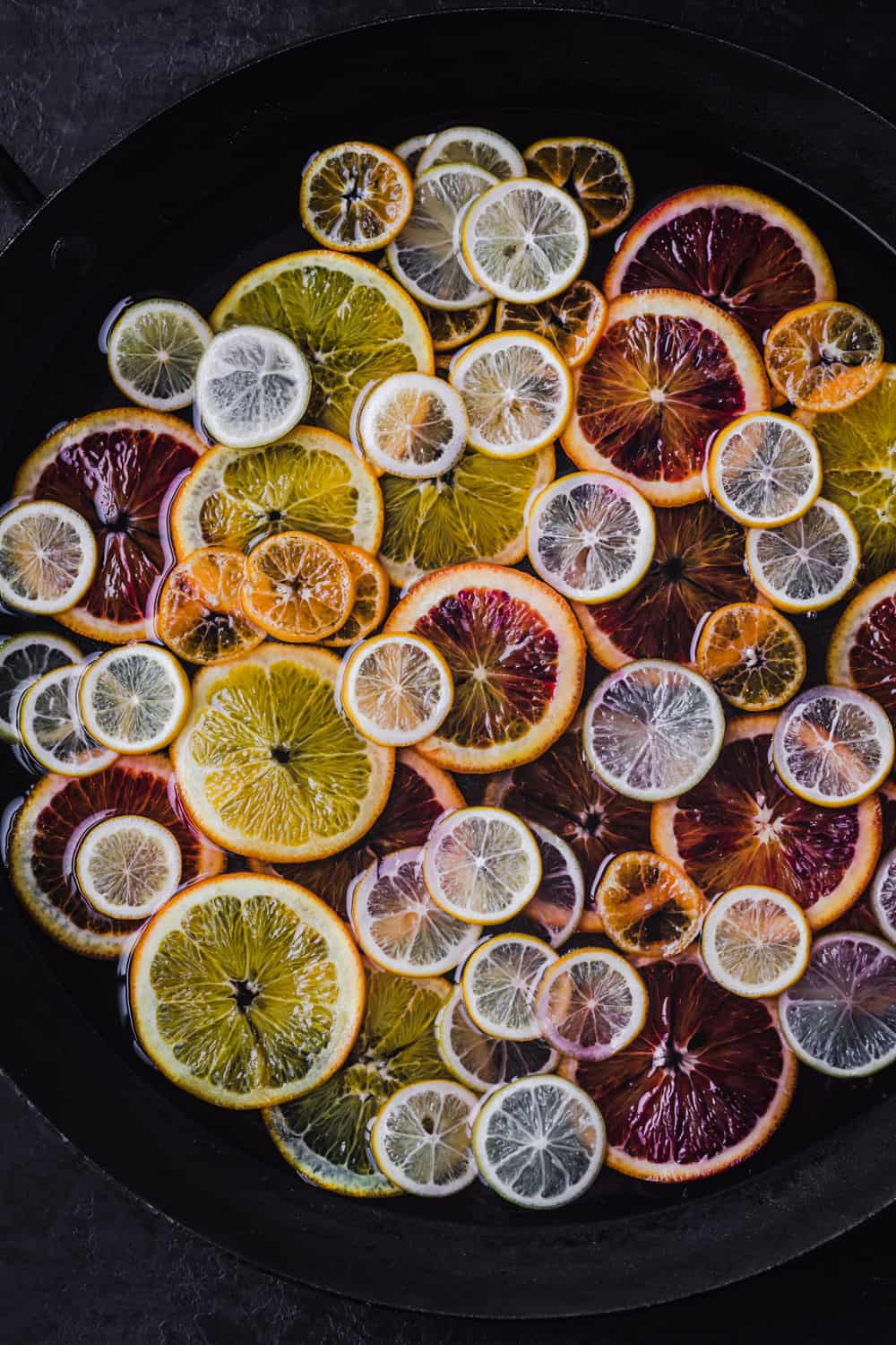 oranges, lemons and limes in saucepan simmering with simple syrup
